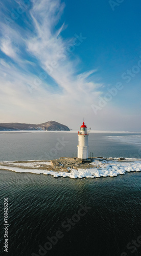 Aerial view of the lighthouse in winter in the ice at dawn