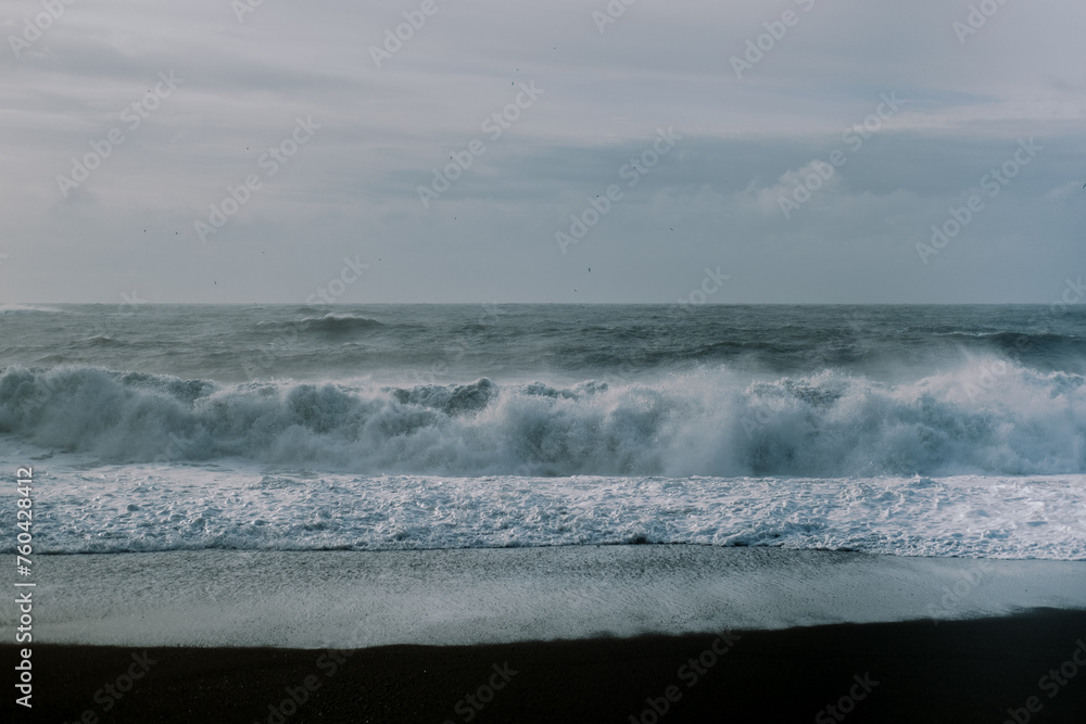 Wave sea background on Iceland black sand beach with cloudy sky
