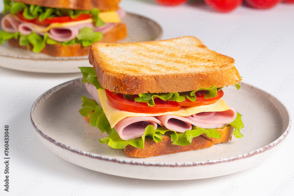 Close-up of two sandwiches with bacon, salami, prosciutto and fresh vegetables on rustic wooden cutting board. Club sandwich concept Close-up of two sandwiches with bacon, salami, prosciutto and fresh vegetables on rustic wooden cutting board. Club sandwich concept
