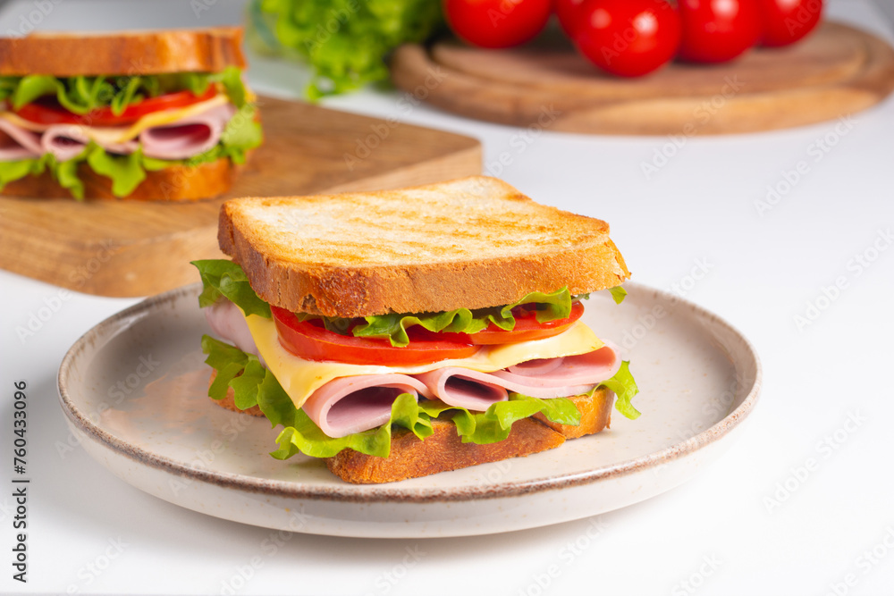 Close-up of two sandwiches with bacon, salami, prosciutto and fresh vegetables on rustic wooden cutting board. Club sandwich concept Close-up of two sandwiches with bacon, salami, prosciutto and fresh vegetables on rustic wooden cutting board. Club sandwich concept