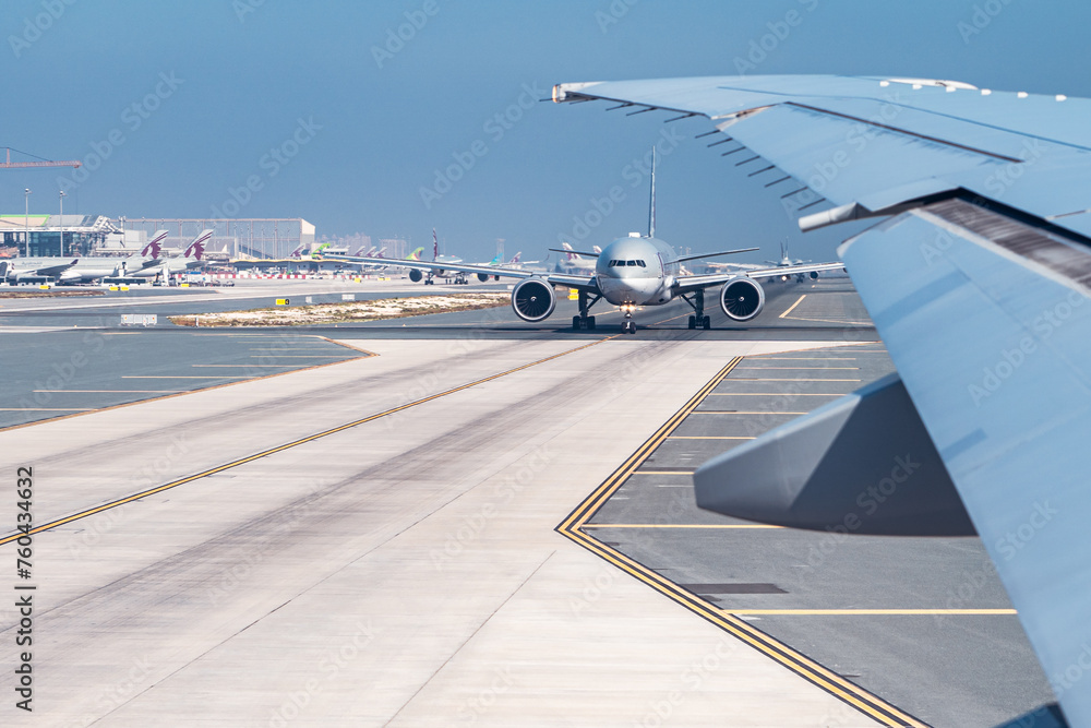 Airplanes taxiing on runway at international airport under clear sky