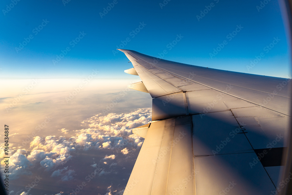 Beautiful sunset, sky on the top view, airplane flying view from inside window aircraft of Traveling. View of the clouds and airplane wing from the Inside. 