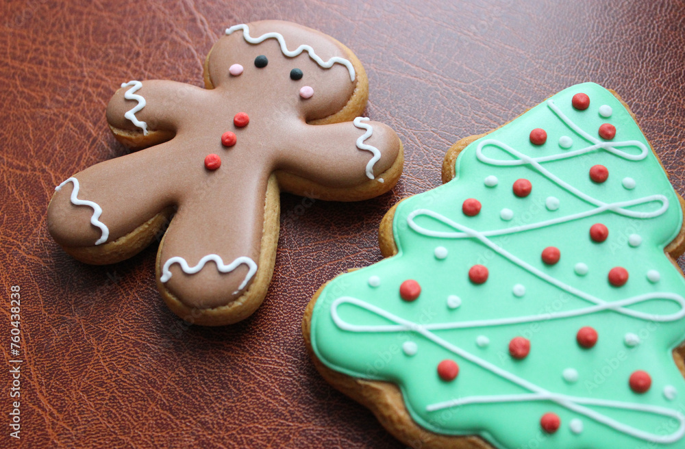 Holidays Background With Gingerbread Man And Pine Tree Cookies With Colored Icing On Leather Folder Closeup Angle View
