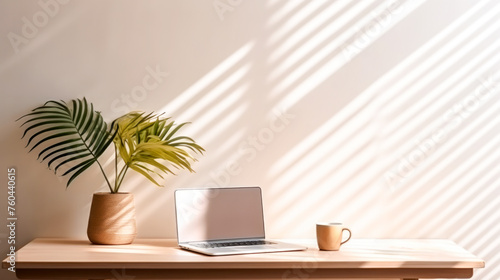 Desktop with laptop  coffee cup and flowerpot with palm tree against a light wall with morning light. The concept of a cozy home office in a Scandinavian style. Generated AI