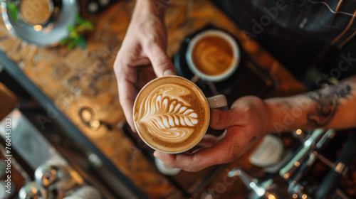 Barista making latte art with coffee in a cafe, close up hand holding a silver milk pot and pouring cream photo