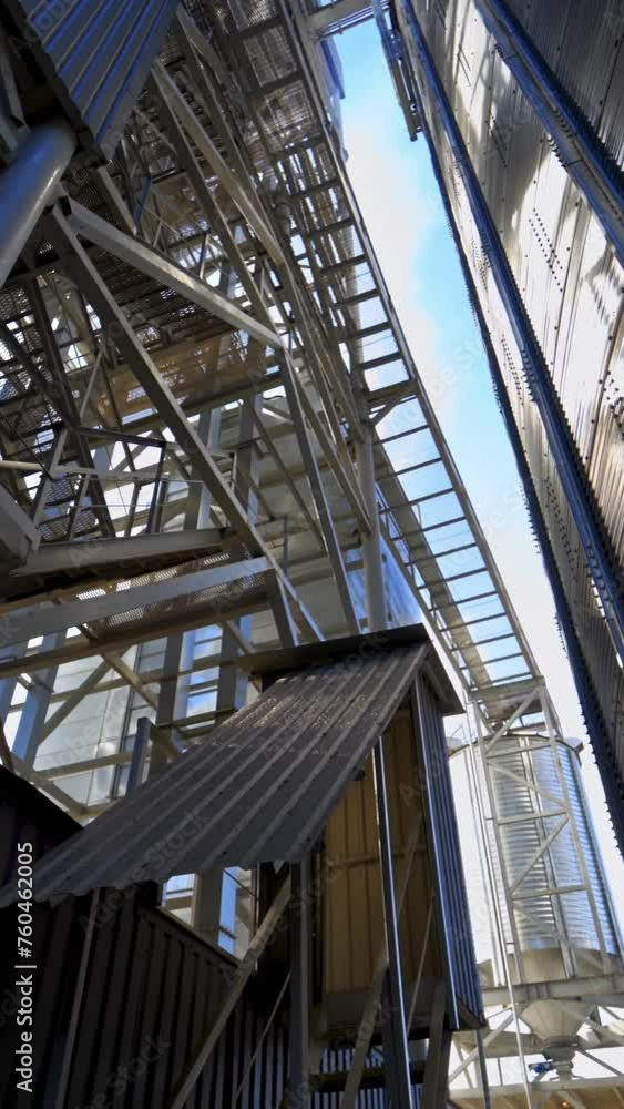Industrial equipment outdoors. Large metal terminals. Silver grain elevators on a modern plant for storing agricultural products. Close-up. Vertical video Industrial equipment outdoors. Large metal terminals. Silver grain elevators on a modern plant for storing agricultural products. Close-up. Vertical video