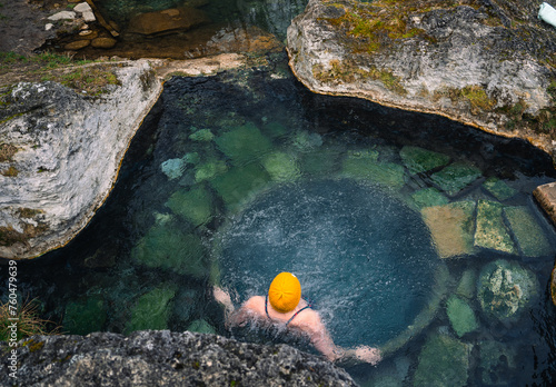 Top view of a natural thermal pool. Woman in a yellow cap relaxing in a thermal bath in Slovakia. In the Low Tatras National Park. Thermal baths almost like in Iceland