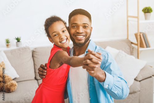 Handsome father and cute daughter dancing at home