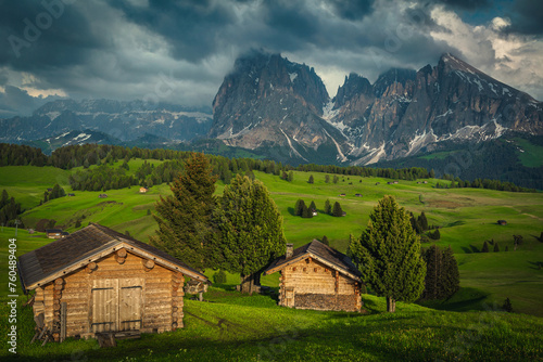 Log huts on the green meadow in the Dolomites, Italy