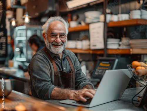 An elderly man exudes joy while using a laptop at a bustling café, showcasing active aging in modern society.