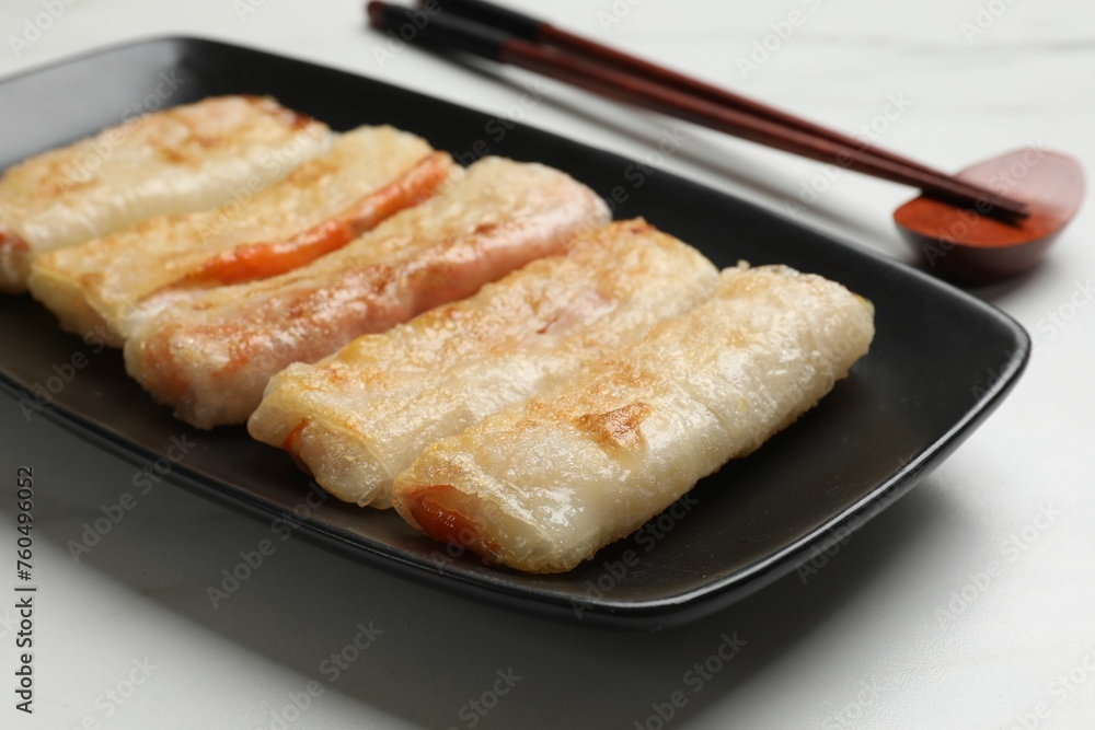 Delicious fried spring rolls and chopsticks on white table, closeup Delicious fried spring rolls and chopsticks on white table, closeup