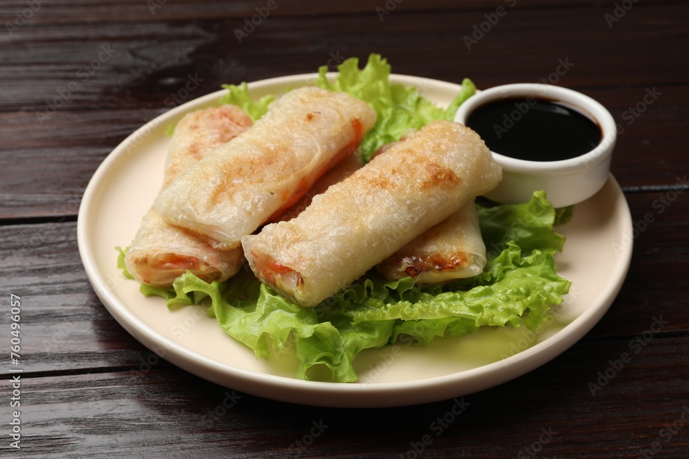 Delicious fried spring rolls with soy sauce on wooden table, closeup Delicious fried spring rolls with soy sauce on wooden table, closeup