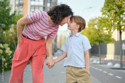 Adorable mother and son smiling happy having fun at city background. Motherhood concept, hugging. Boy 8 years old with mother in bright clothes enjoying summer day. High quality photo