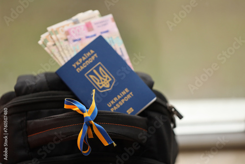 Ukrainian biometrical passport and UAH money bills on touristic backpack close up