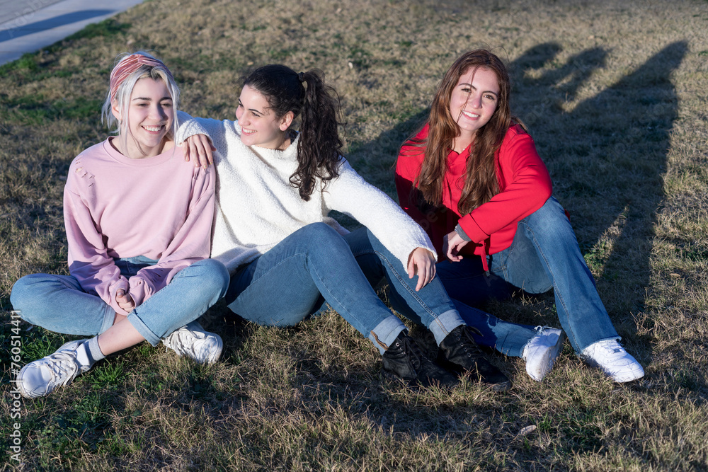 Three friends relaxing on grass in sunlight Three friends relaxing on grass in sunlight