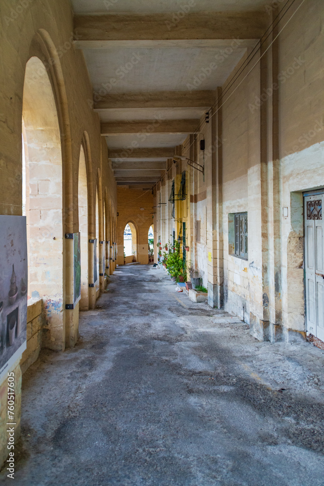 Obraz premium Triq L-Arkati, Senglea, Malta - December 3rd 2018: Covered street in the fortified city. One of the Three Cities in the Grand Harbour area which was given the title Civitas Invicta (Unconquered City)