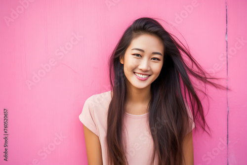 Portrait of happy young asian woman in front of the pink wall
