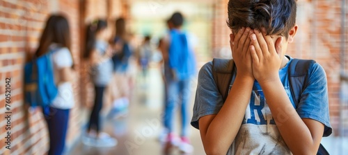 Distraught teenage boy crying in school corridor, blurred background, learning difficulties concept