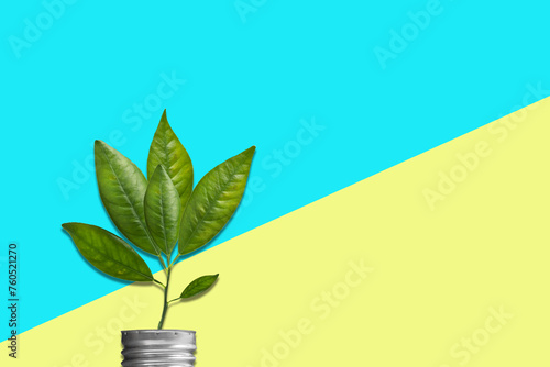 Green energy concept. Light bulb socket with sprout, green leaves on a yellow-blue background. Ecology. Environment protection. Ecological