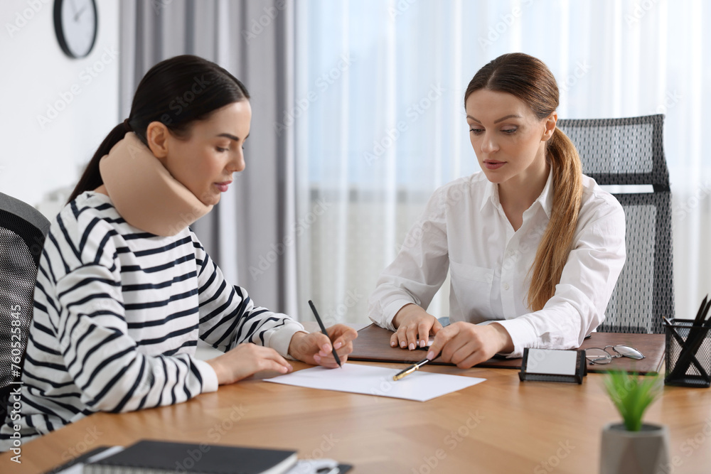 Injured woman signing document in lawyer's office Injured woman signing document in lawyer's office