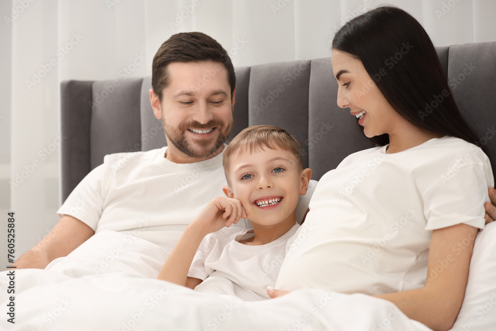 Pregnant woman with her son and husband in bed at home. Happy family