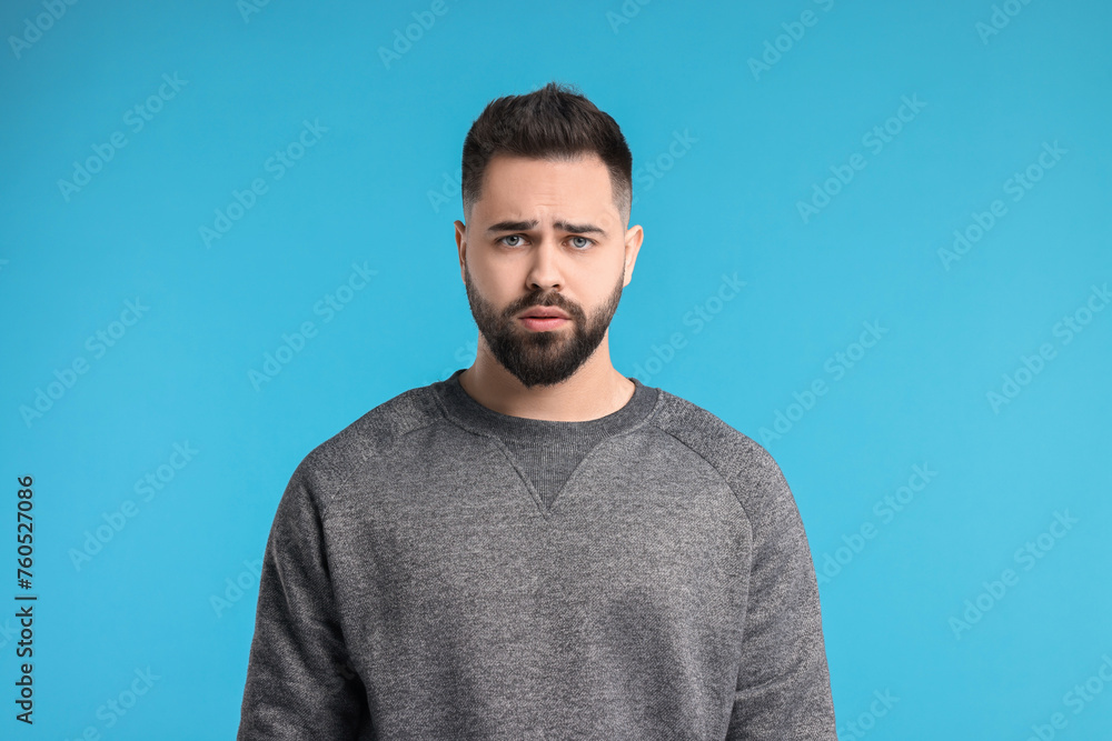 Portrait of sad man on light blue background Portrait of sad man on light blue background