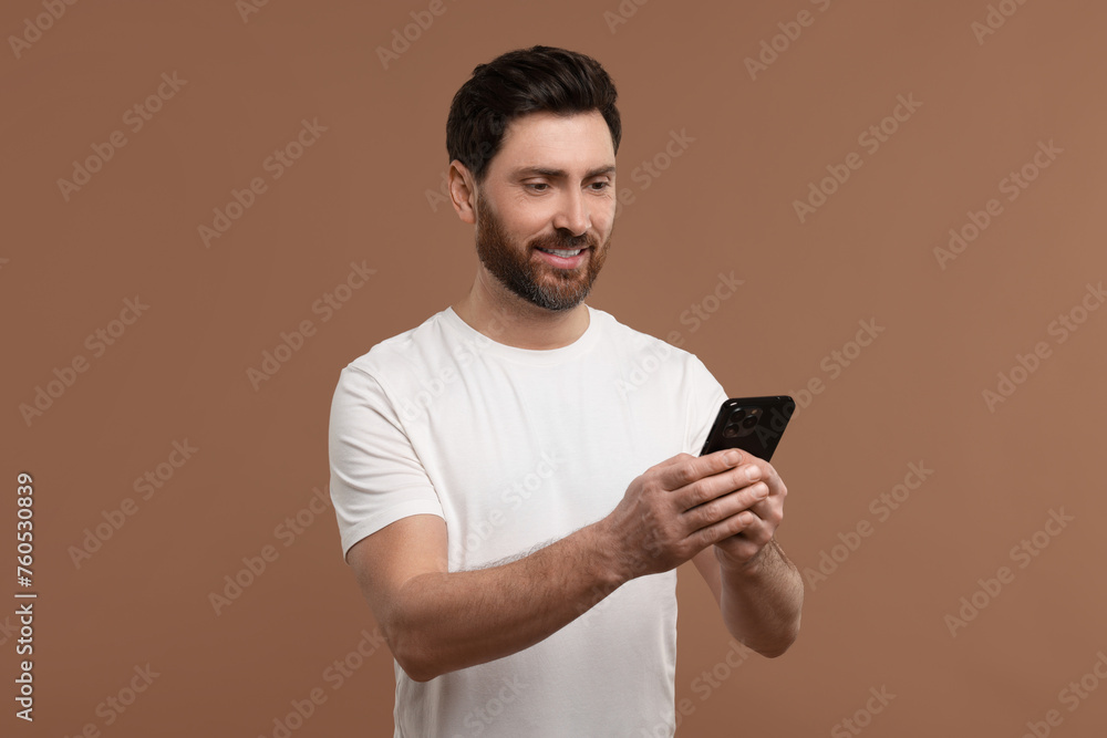 Smiling man with smartphone on light brown background Smiling man with smartphone on light brown background