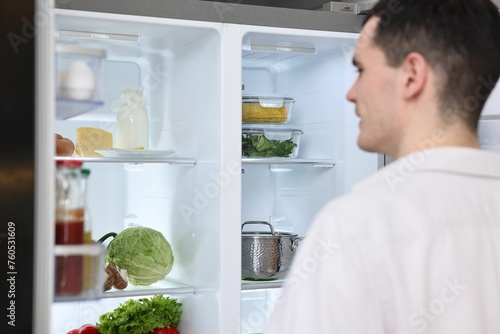 Man near refrigerator in kitchen at home, selective focus
