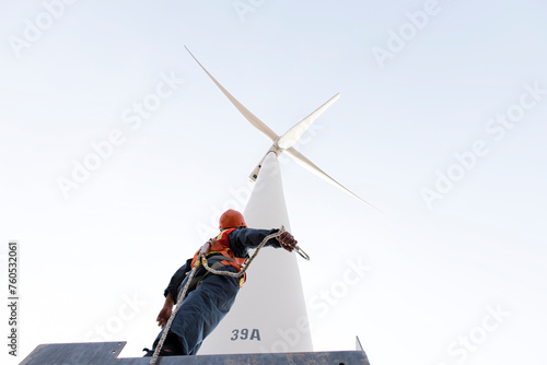  Maintenance engineer standing against turbines on wind turbine farm.