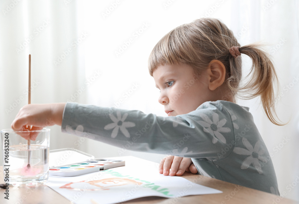 Cute little girl drawing with brush at wooden table indoors. Child`s art Cute little girl drawing with brush at wooden table indoors. Child`s art