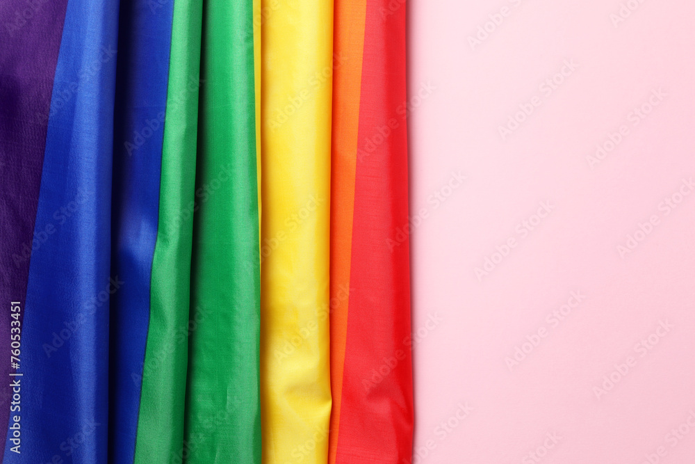 Rainbow LGBT flag on pink background, top view. Space for text