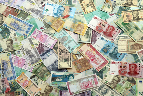 Many banknotes of different currency. Background of big amount of random money bills close up