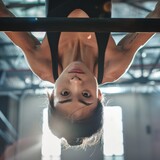 asian female gymnast hanging upside down on the uneven bars in a bright gym
