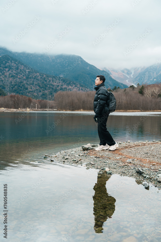 man  tourist travel Kamikochi National Park, happy Traveler sightseeing Taisho pond with mountain, Nagano Prefecture, Japan. Landmark for tourists attraction. Japan Travel, Destination and Vacation
