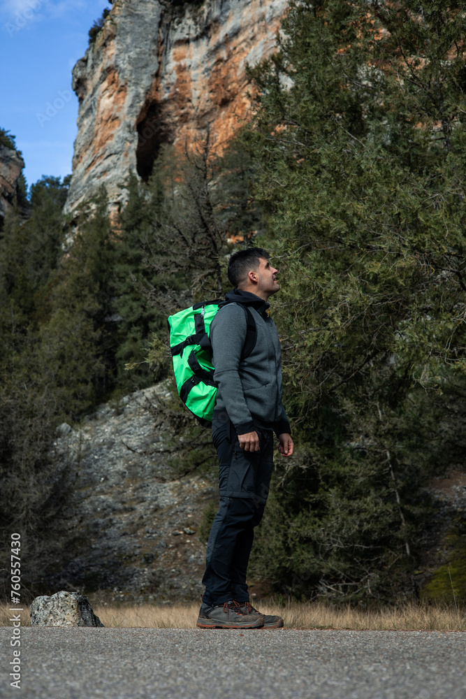 Young Hiker with green backpack Contemplates Nature's Majesty Amidst the Woods