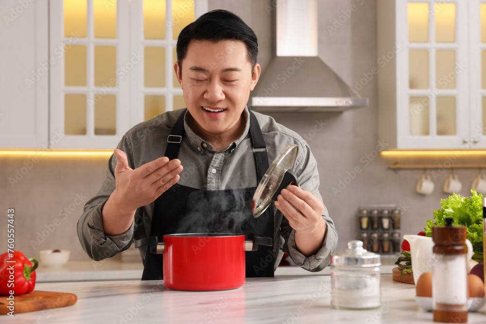 Man with pot smelling dish after cooking at countertop in kitchen Man with pot smelling dish after cooking at countertop in kitchen