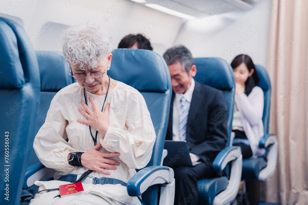 Obraz premium 飛行機の機内で体調不良に苦しむ高齢の女性