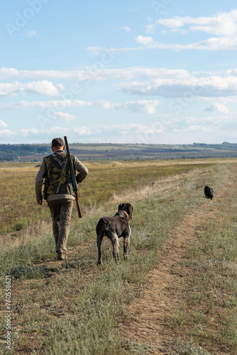 Mature man hunter with gun while walking on field with your dogs © Budjak Studio