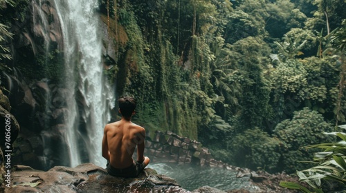 A man looking at waterfall on jungle, forest in the background.