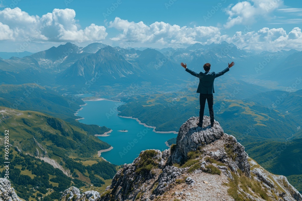 A businessman stands on a rocky mountain peak with arms raised in victory, overlooking a stunning landscape with a serpentine lake nestled among lush green valleys and rugged mountain ranges A businessman stands on a rocky mountain peak with arms raised in victory, overlooking a stunning landscape with a serpentine lake nestled among lush green valleys and rugged mountain ranges