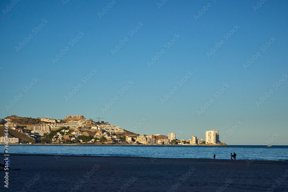 A scenic coastal town with a vibrant beach and colorful buildings under a blue sky. Captures the idyllic atmosphere of a relaxing seaside paradise.