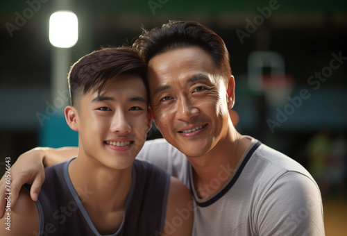 Portrait of an Asian father and son, indoors at the sports field. Basketball