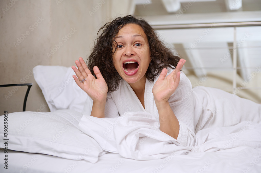 Portrait of an excited young woman lying on the bed in the morning, enjoying her weekend at home Portrait of an excited young woman lying on the bed in the morning, enjoying her weekend at home