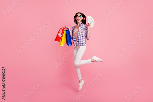 Full length side profile body size photo beautiful her she lady jump high just left shop packs dollars hands arms wear shoes hat casual checkered plaid shirt white jeans denim isolated pink background