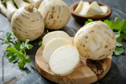 Jicama vegetable sliced on a wooden board with fresh parsley and whole jicamas in the background photo