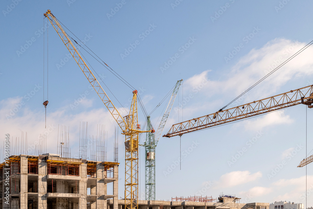 The construction process of a multi-storey residential building, construction cranes, a house under construction.