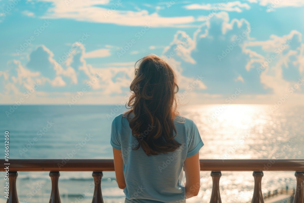 Woman standing on balcony overlooking the ocean. Suitable for travel and relaxation concepts