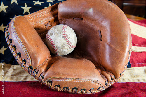 Foto old worn baseball in leather catcher's mitt on tea stained American flag