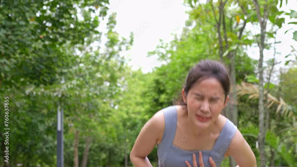 Asian young runner workout standing bent over and catching her breath and suffering from heat stroke and heart attack outdoors after running workout on urban city forest park Asian young runner workout standing bent over and catching her breath and suffering from heat stroke and heart attack outdoors after running workout on urban city forest park