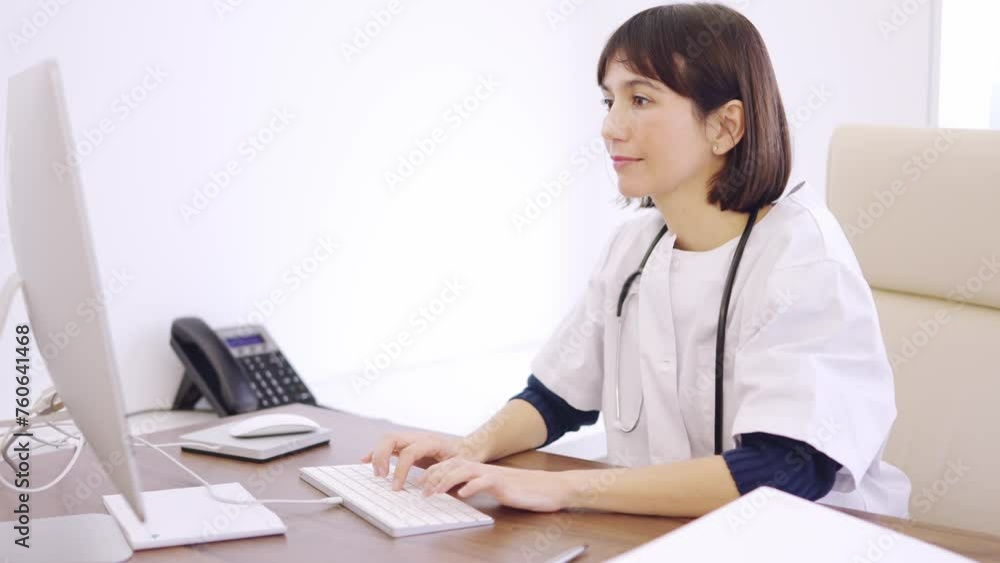 Female doctor using computer and smiling at camera in clinic Female doctor using computer and smiling at camera in clinic